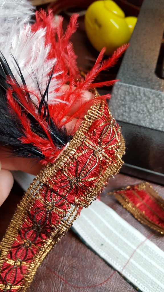 Stitch piece of trim over band to cover bottom of feathers.