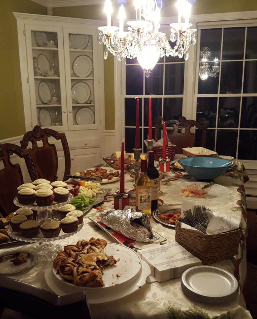 From center front - hazelnut pastry (made by emma), red velvet cupcakes, stollen, veggies, chicken wings, cheese, crackers and bread, crab dip, black eyed peas, shrimp, bruschetta. 